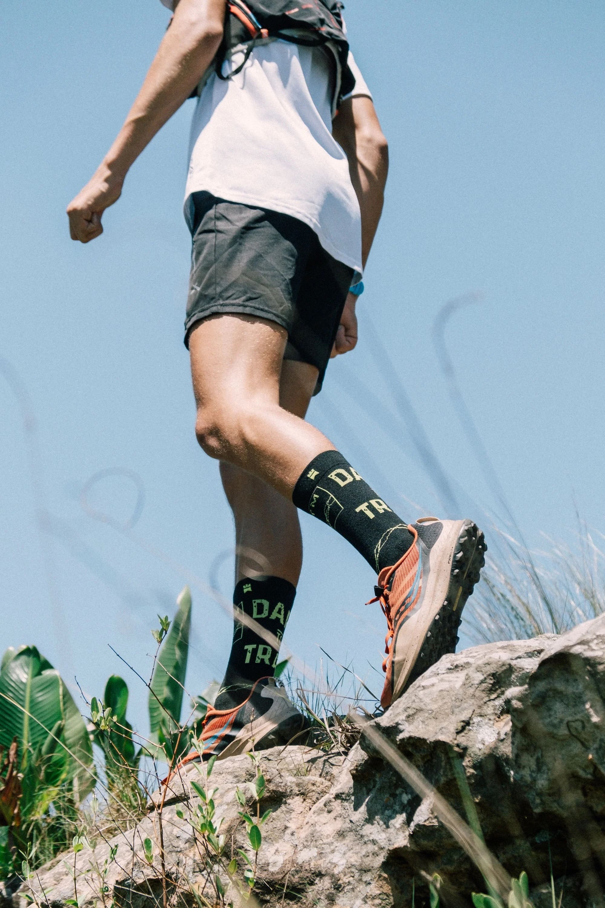 Travis Brigg standing on a rock in a pair of Dare to Trail crew height socks.